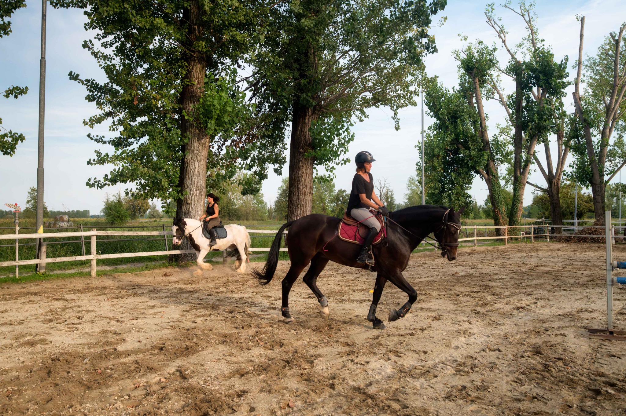 Due amazzoni nel campo esterno del Remolino, una su un cavallo scuro in primo piano e l’altra su un cavallo pezzato, durante una lezione.