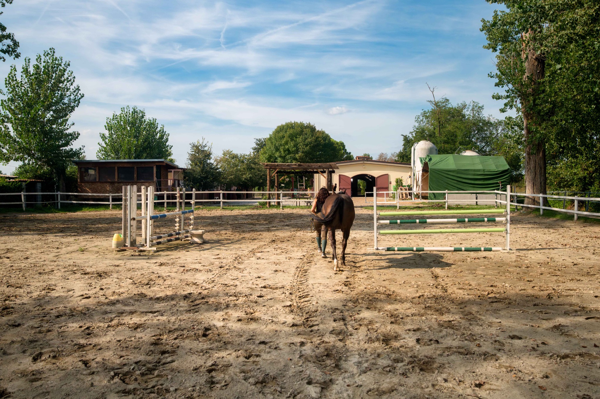Campo esterno del Remolino con ostacoli, una persona che conduce un cavallo a mano e la club house sulla sinistra.