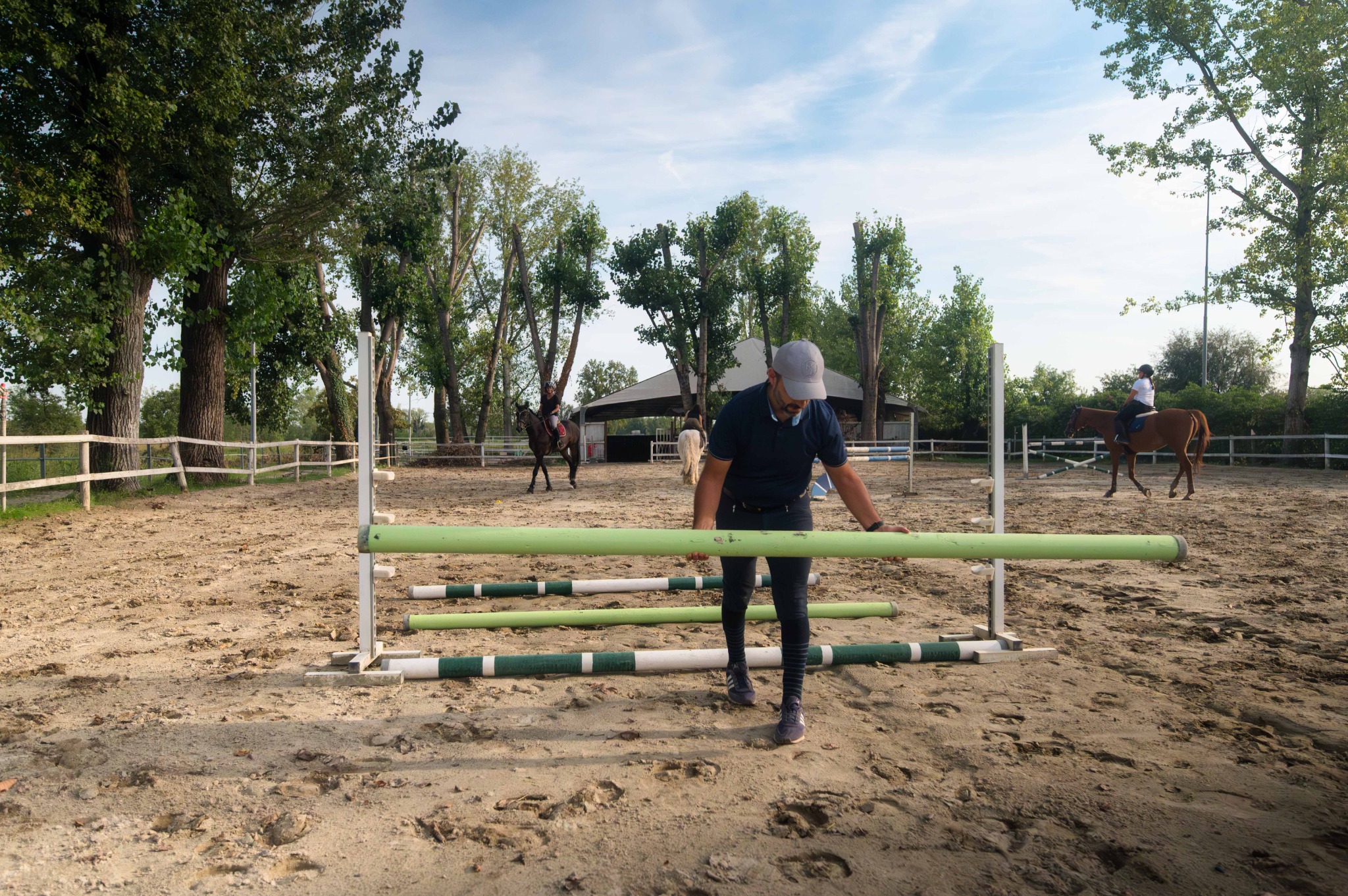 L’istruttore qualificato sistema una barriera nel campo esterno del Remolino, con alcune amazzoni a cavallo sullo sfondo.