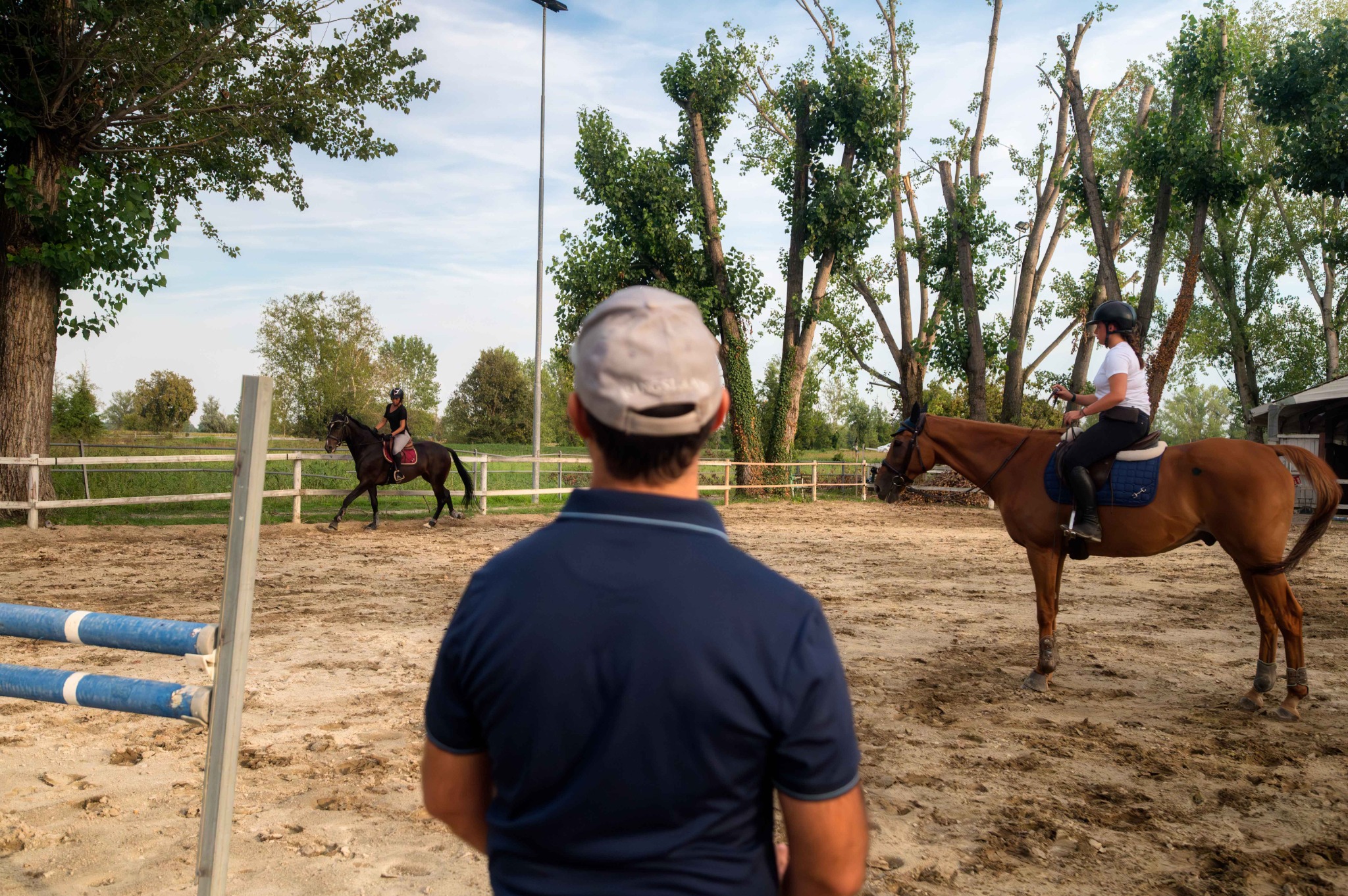 L’istruttore qualificato, ripreso di spalle, dà lezione a due amazzoni nel campo esterno del Remolino.