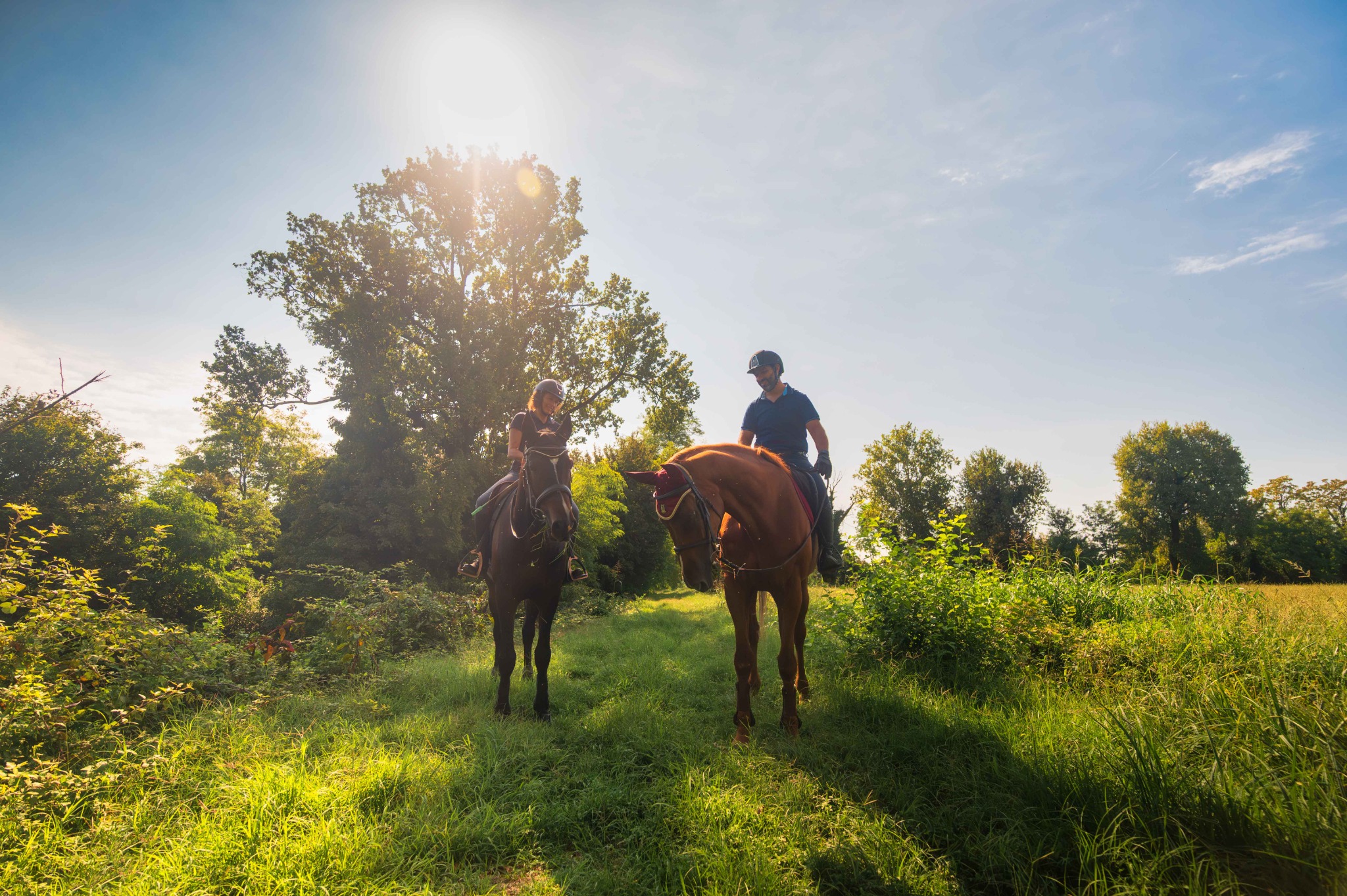 Due cavalieri su un sentiero erboso tra alberi e campi nei dintorni del Remolino.
